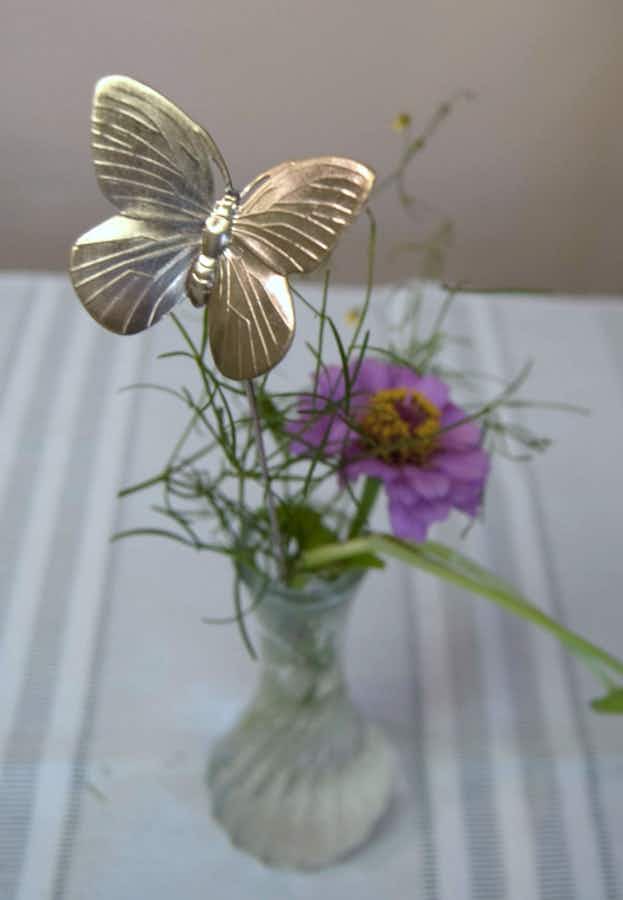 Butterfly Plant Stick in a vase with greens and a flower