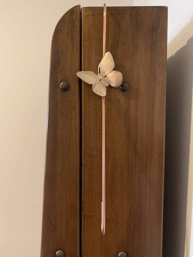 Copper coated extension hook with a brass butterfly hanging on cabinet