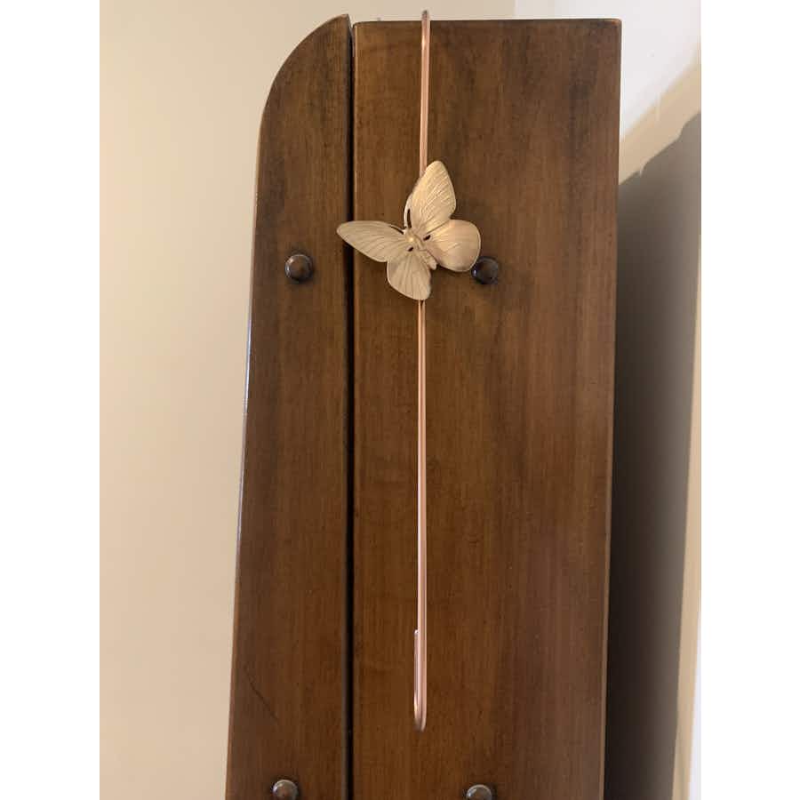 Copper coated extension hook with a brass butterfly hanging on cabinet