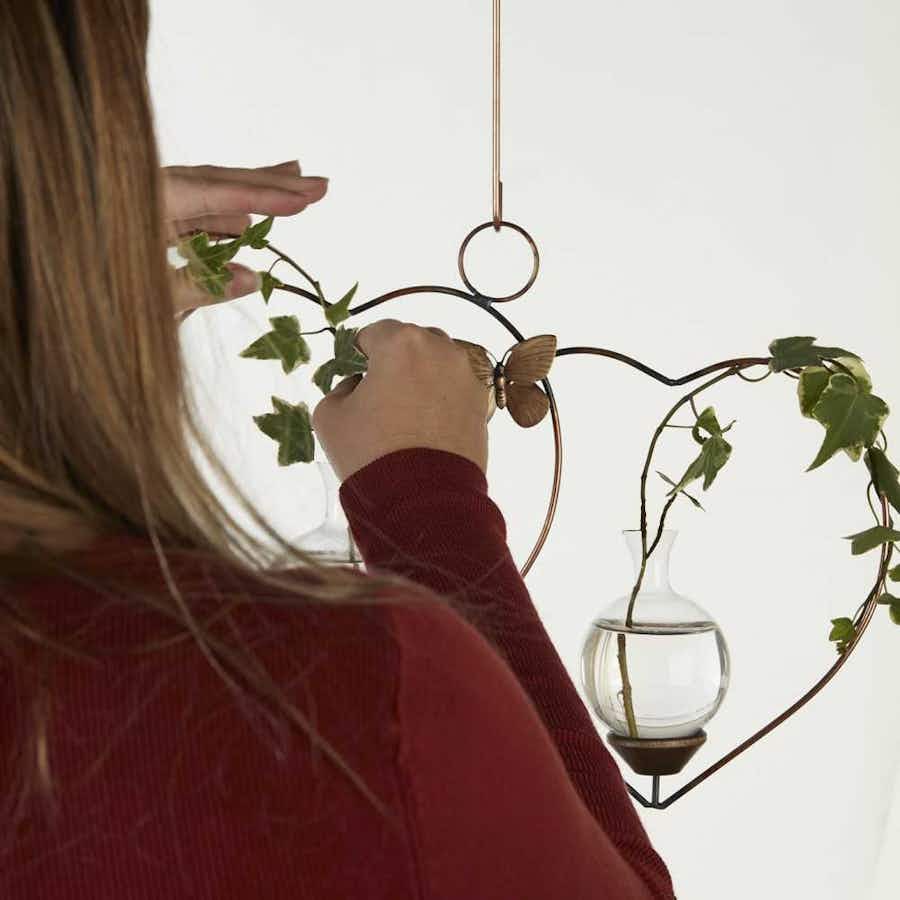 Person putting plant cuttings in Double Heart Hanging Plant Propagation Rooter Vase